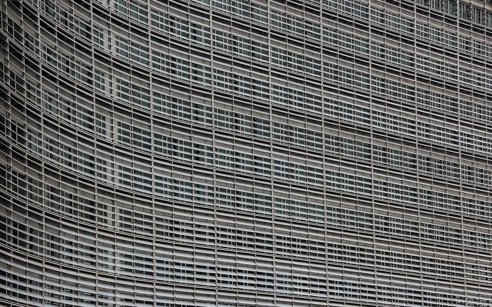 The Berlaymont building facade, European Commission headquarters, Brussels, photographed from street level showing the glass curtain wall and the EU flag