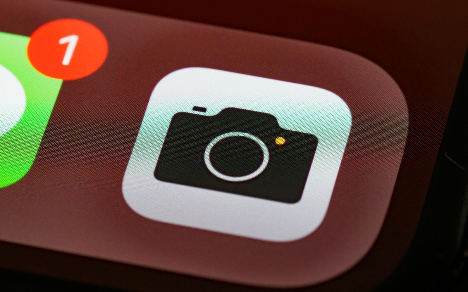 Close-up of a smartphone camera app icon beside a notification badge showing one alert