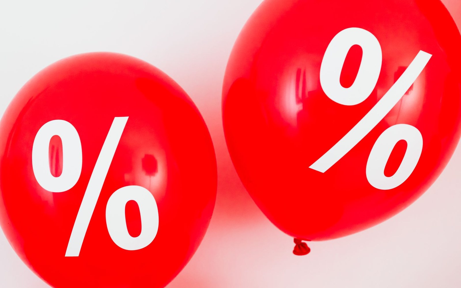 Two red balloons printed with large white percentage symbols against a light background
