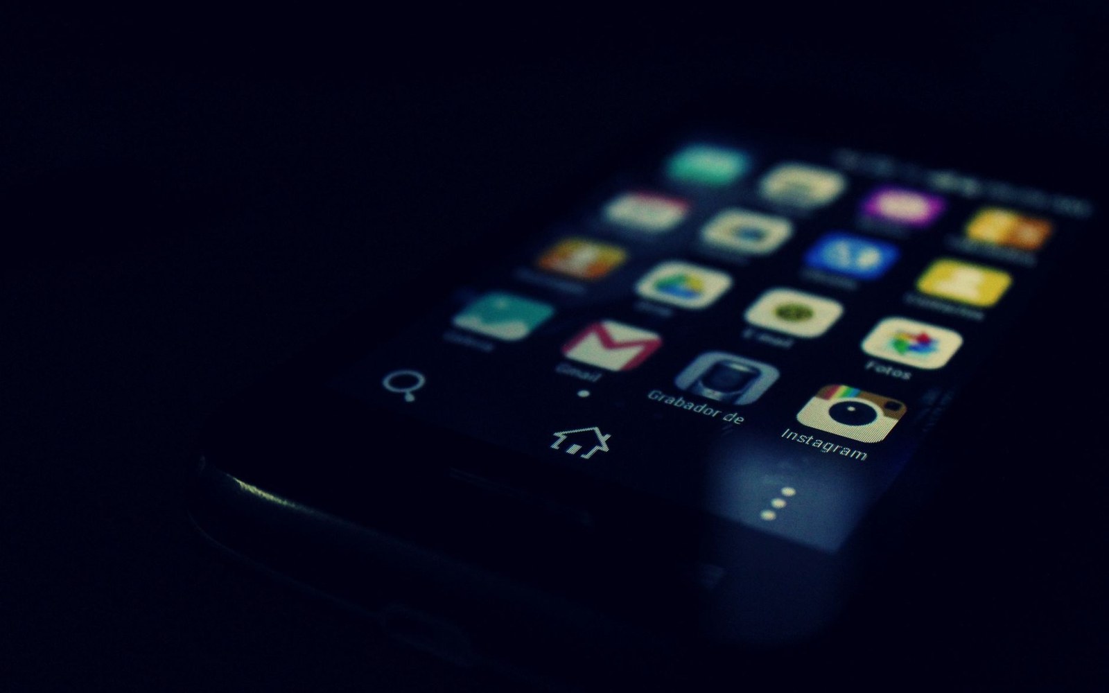 Smartphone screen glowing in the dark, showing a home screen with app icons including Instagram and Gmail