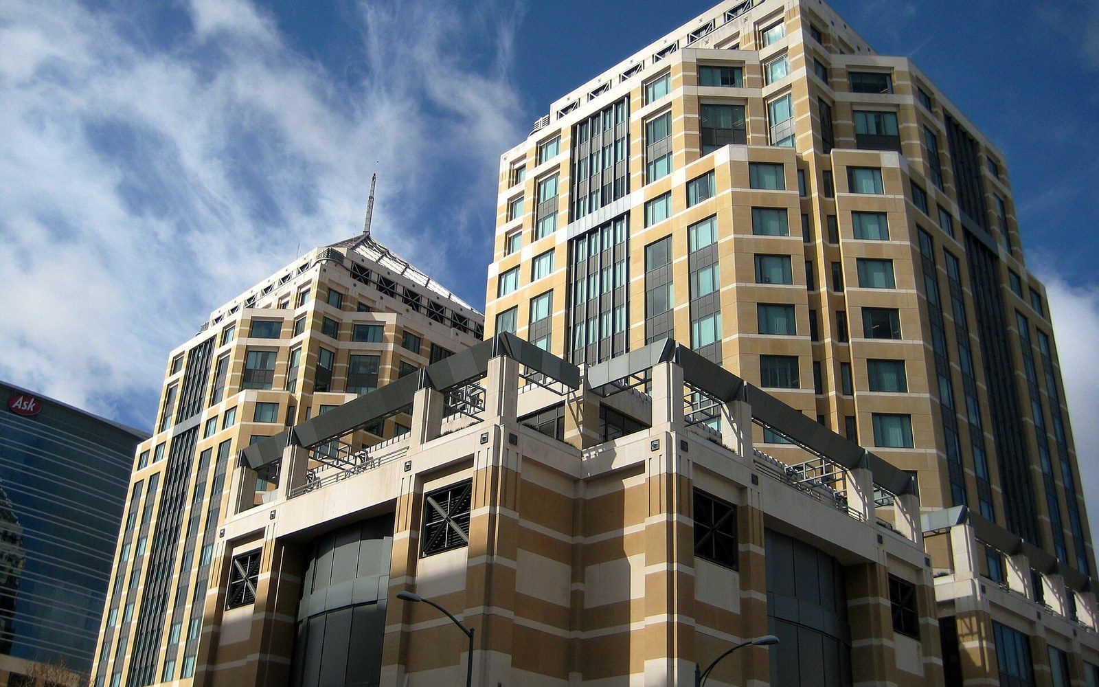 Twin high-rise towers with tan and white facades against a blue sky